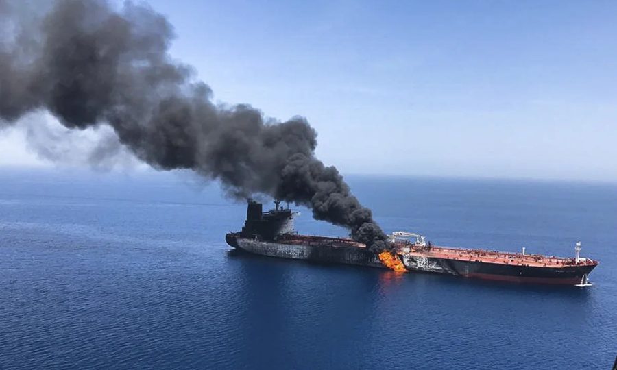 An oil tanker on fire at sea, with black smoke rising